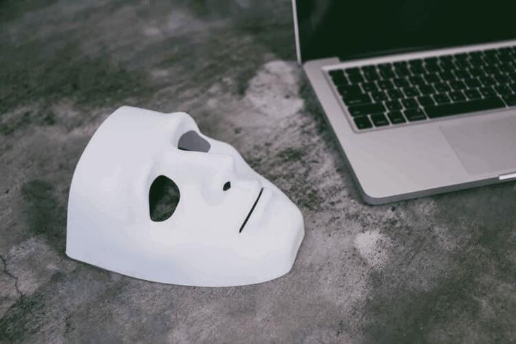 Masque d'escroc posé à côté d'un ordinateur signifiant une escroquerie sur internet ou une usurpation d'identité