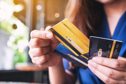Une personne tient dans sa main trois cartes bleues. Ces cartes bancaires sont utilisées pour représenter l'assurance moyens de paiement.