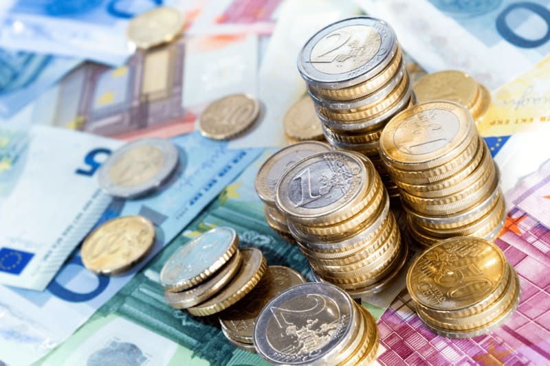 argent avec piles de pièces de monnaie euro sur des billets en vrac