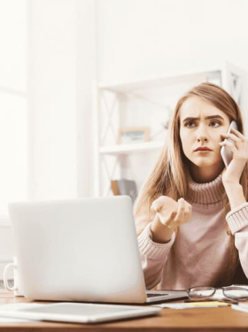 femme mécontente au téléphone devant son ordinateur assise dans son bureau