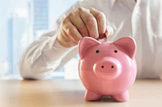 Main déposant une pièce dans une tirelire rose en forme de cochon