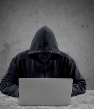 escroc en capuche cachant son visage devant son ordinateur